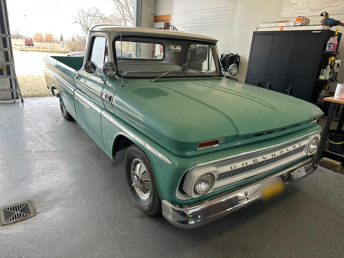 Mint-green Chevrolet pickup with white roof inside a clean garage bay